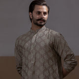 Arsalan Iqbal Beige Classic Chikankari Kurta Pyjama man wearing a beige full sleeve kurta with intricate white chikankari floral embroidery, mandarin collar, and a relaxed tailored fit, styled in a warm indoor setting