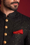 Extreme close-up of Arsalan Iqbal luxury black sherwani featuring tonal floral embroidery with silver sequins, decorative gold embossed buttons, and a textured red silk pocket square.