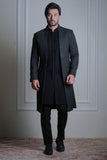 Male model wearing a black sherwani by Arsalan Iqbal, modern formal ethnic menswear in an elegant indoor setting