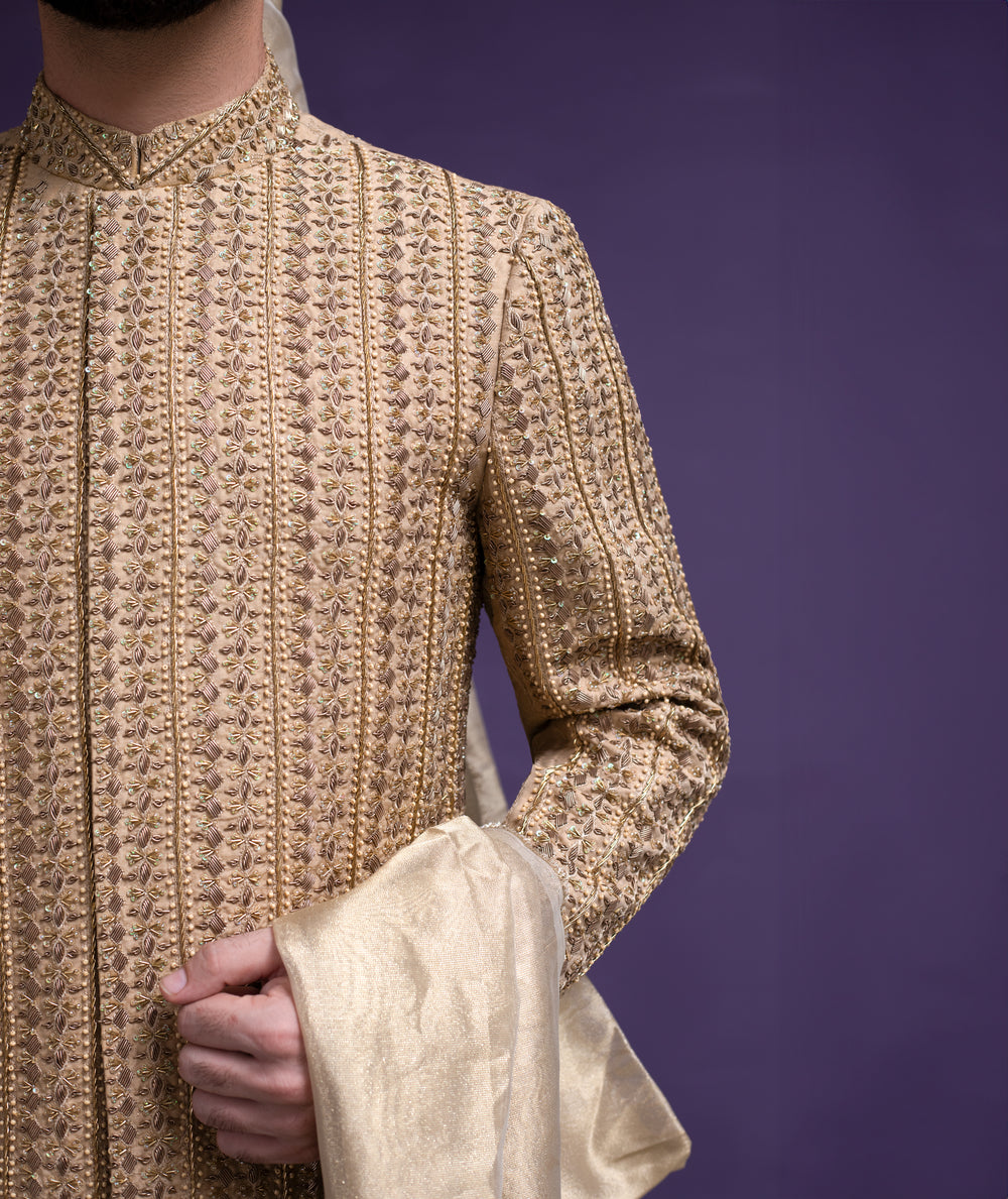 Extreme close-up of Arsalan Iqbal gold sherwani showing intricate vertical hand-embroidery, sequin work, and premium fabric texture with a silk dupatta.