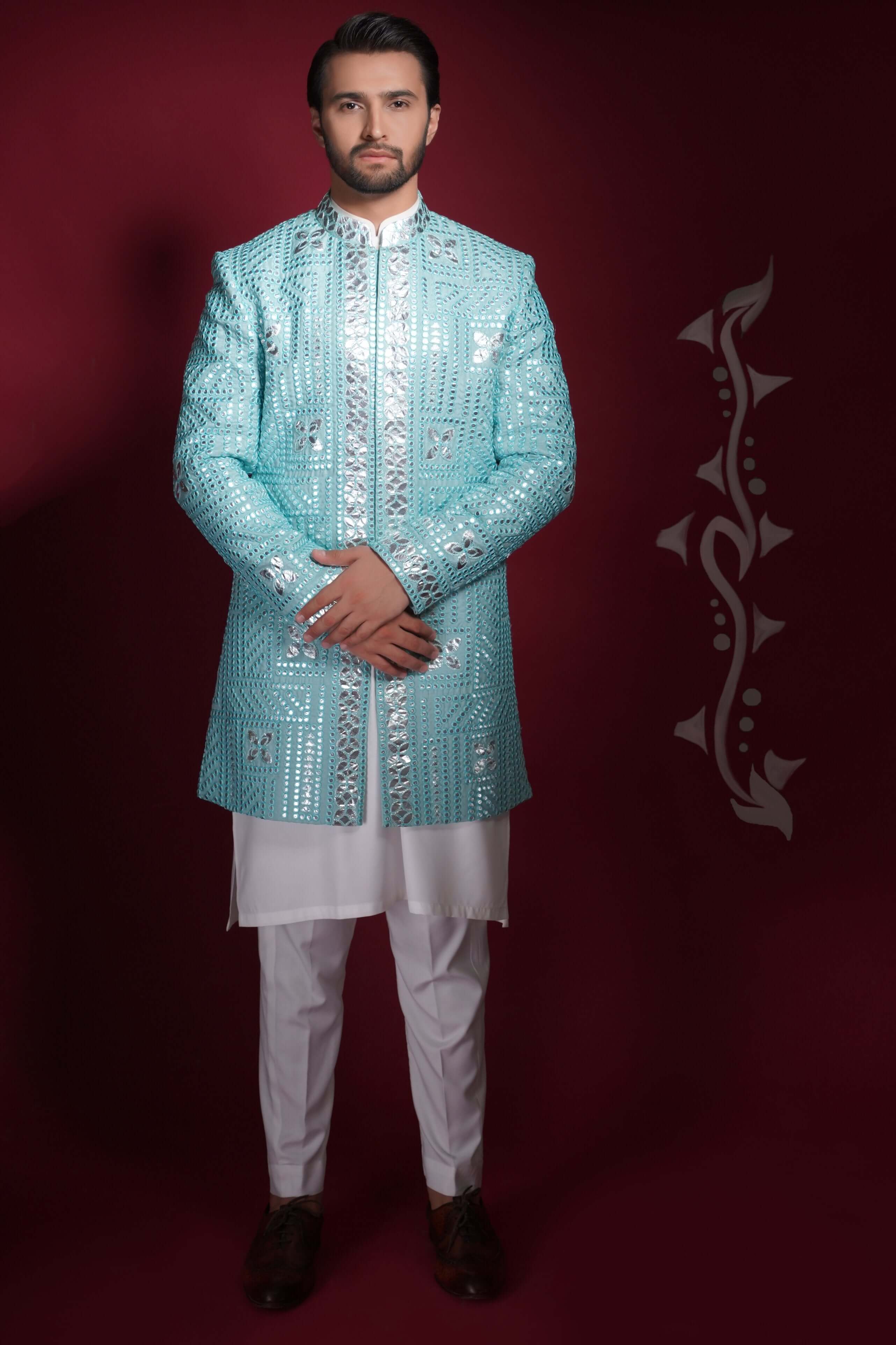 Arsalan Iqbal ice-blue prince coat featuring silver mirror-work in a geometric grid pattern, worn over a white long tunic and trousers.