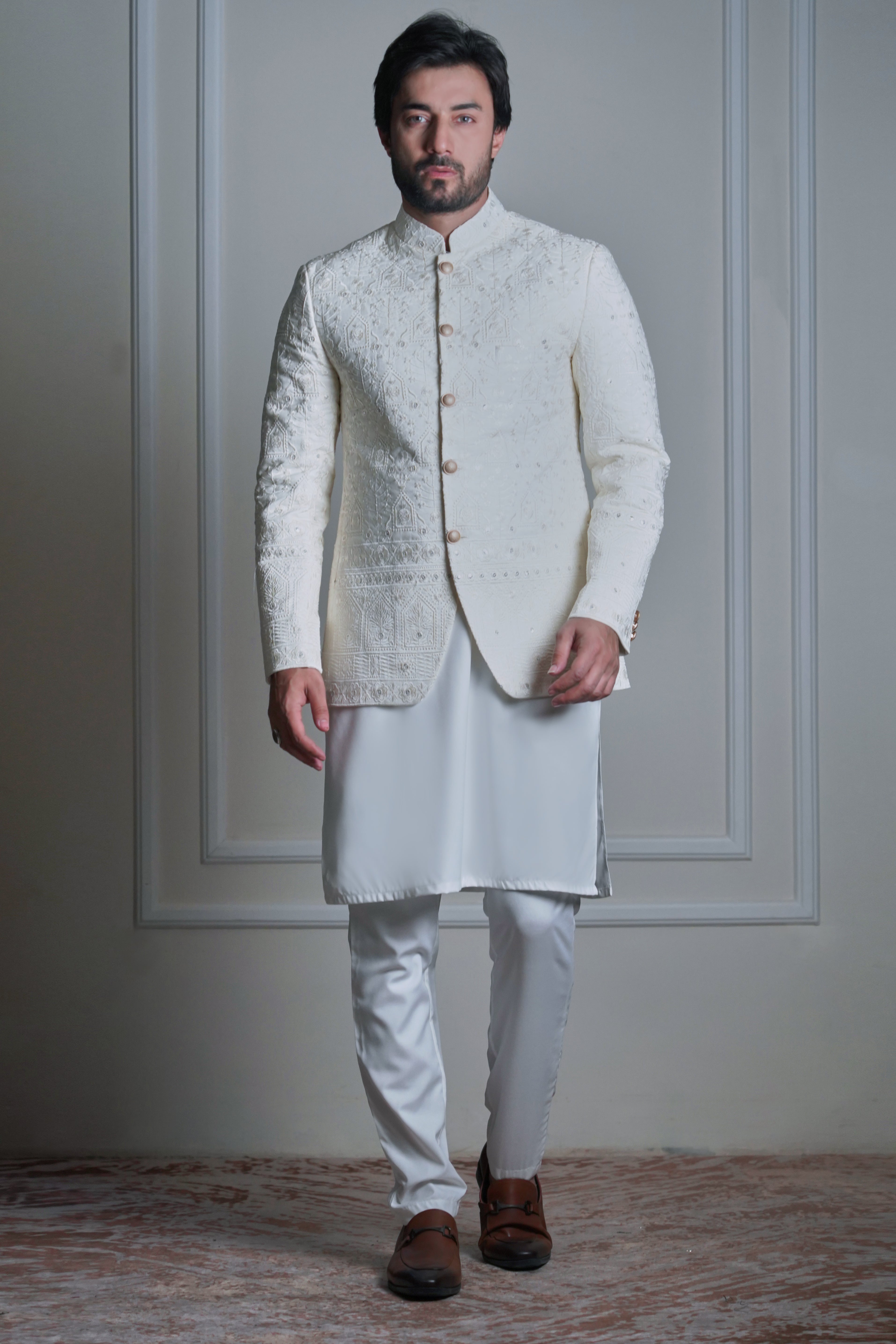 Model wearing an ivory embroidered sherwani with white kurta pajama and brown leather loafers by Arsalan Iqbal