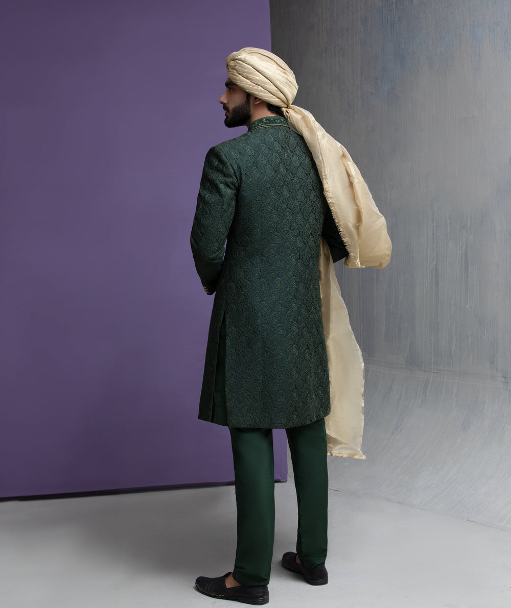 Arsalan Iqbal forest green designer sherwani with matching trousers, gold shawl, and traditional beige turban in a full-length shot