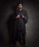 Arsalan Iqbal premium midnight black sherwani for men with tonal hand-embroidery, styled with a matching black turban, a draped silk shawl, and black traditional trousers.