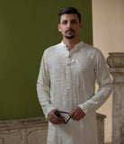 Man wearing Arsalan Iqbal's Off-White Ivory Kurta with allover silver and gold sequin embroidery, styled with black sunglasses against a deep green background