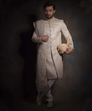 Full-length view of Arsalan Iqbal pearl cream quilted sherwani for grooms, featuring a diamond pattern, embroidered collar and cuffs, styled with a matching embroidered shawl, cream trousers, and traditional mojari shoes.