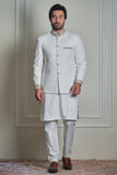 Men’s ivory jacquard prince coat with gold detailing, styled with matching kurta and churidar, formal wedding wear look.