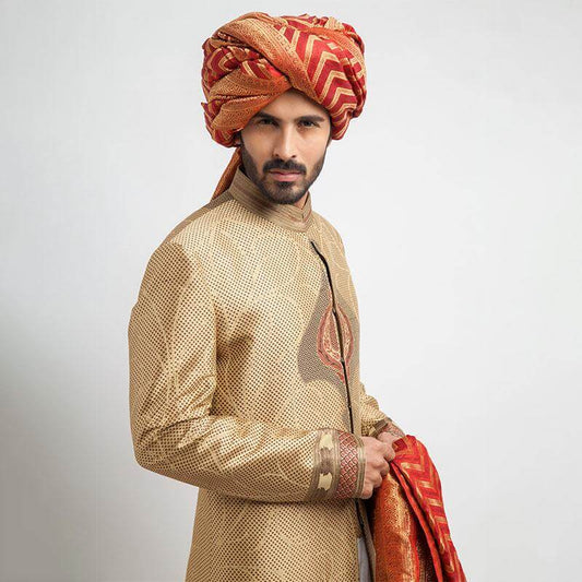 Antique gold, grey, and red brocade sherwani with a form-fitted cut, featuring intricate patterns and rich detailing for a regal appearance.