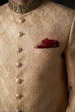 Arsalan Iqbal gold silk sherwani with an ogee-patterned damask weave, featuring embossed metal buttons and a ruby-red silk pocket square.