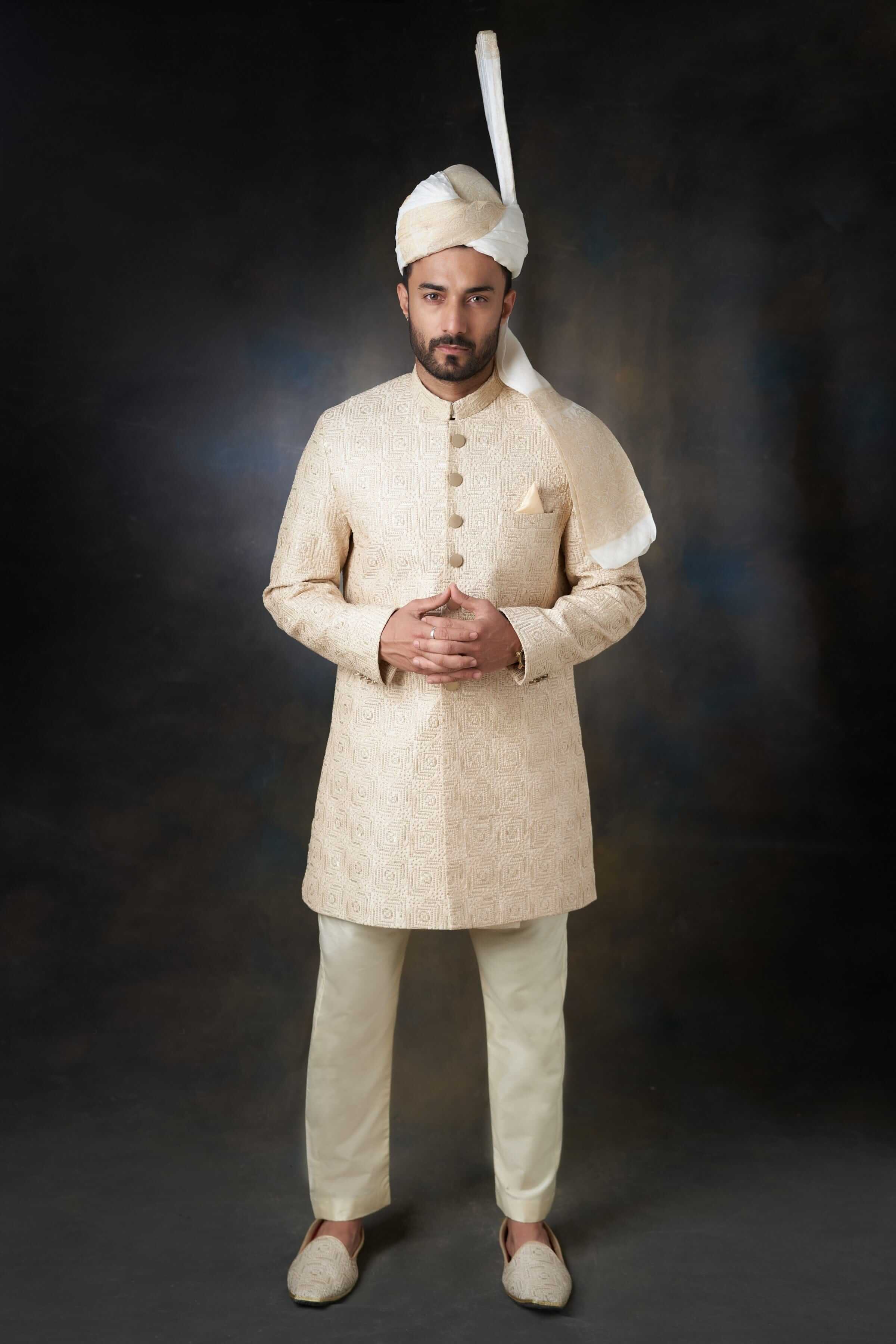 Arsalan Iqbal ivory silk sherwani featuring intricate self-on-self swirl embroidery, gold-toned buttons, and a matching pocket square, paired with a traditional ivory and white turban.
