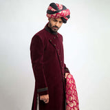 Side view of a man in an Arsalan Iqbal maroon velvet sherwani highlighting the craftsmanship of the cuffs and turban.
