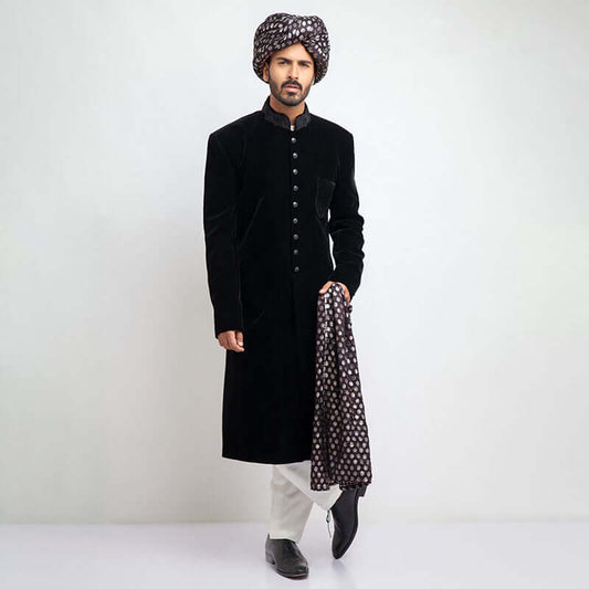 Full-length view of an Arsalan Iqbal black velvet sherwani paired with a silver polka dot turban, matching shawl, and white trousers.