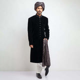 Full-length view of an Arsalan Iqbal black velvet sherwani paired with a silver polka dot turban, matching shawl, and white trousers.