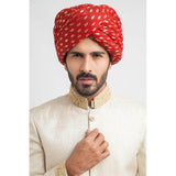 Close-up headshot of an Arsalan Iqbal cream jamawar sherwani with an intricately embroidered gold mandarin collar and a vibrant red and gold polka dot silk turban.