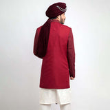 Back view of an Arsalan Iqbal teal paisley jamawar sherwani highlighting the drape of a white brocade shawl and the tailored fit.
