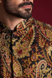 Extreme close-up of Arsalan Iqbal luxury silk sherwani featuring a rich amber, gold, and red paisley tapestry pattern with intricate gold thread embroidery and red bead accents.