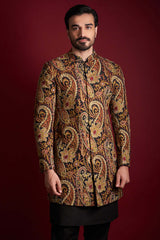 Front-facing view of Arsalan Iqbal luxury short-length silk sherwani featuring a multi-colored amber, gold, and red paisley tapestry print with a mandarin collar, paired with black trousers.