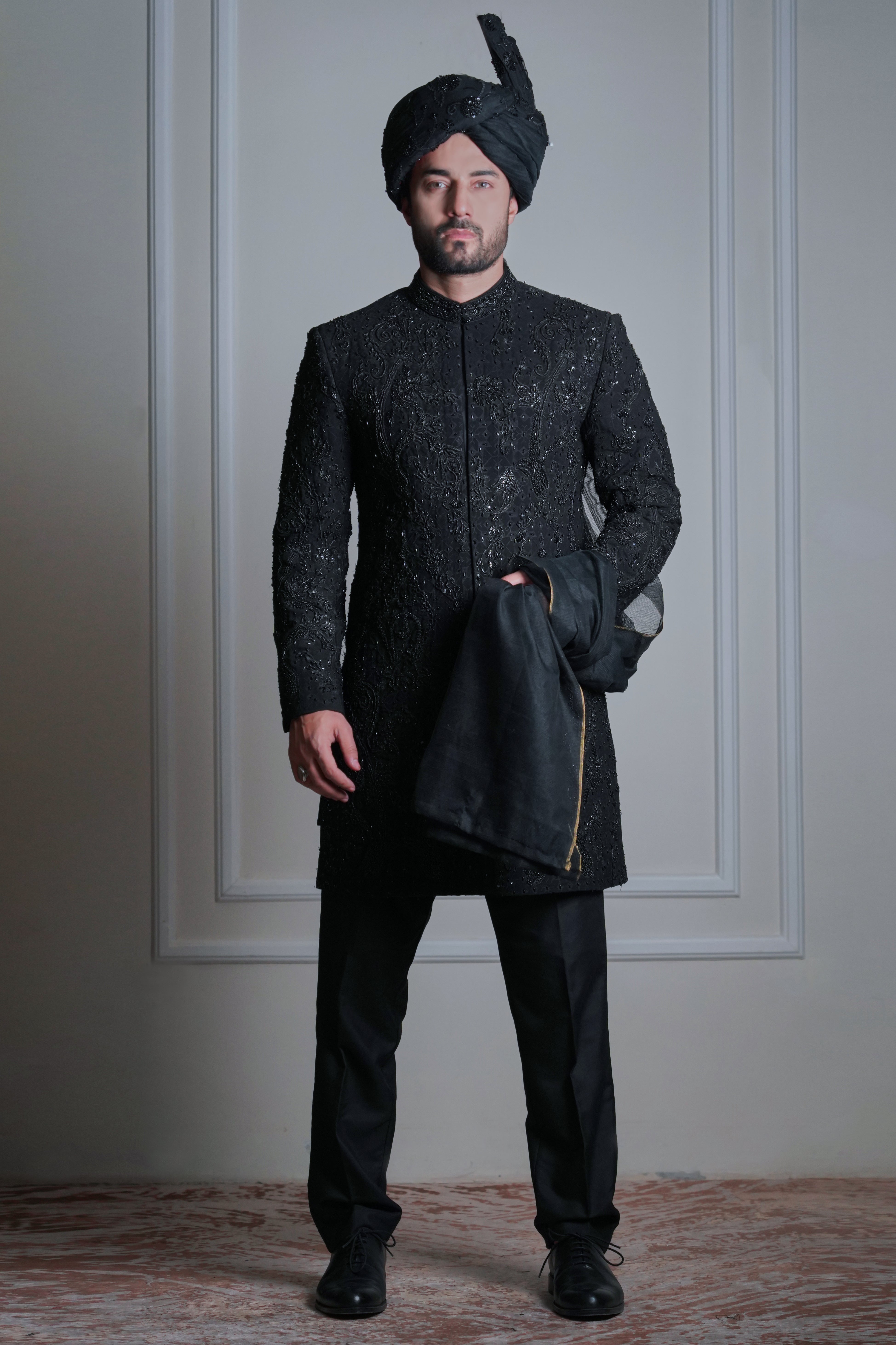 Male model wearing a black embroidered sherwani with turban by Arsalan Iqbal, luxury groom and wedding menswear