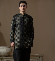 Man wearing Arsalan Iqbal's Black Kurta with allover gold metallic embroidery, styled with sunglasses and a silver watch against a dark background