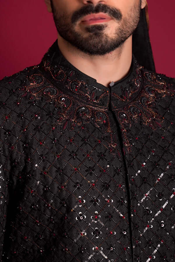 Extreme close-up of Arsalan Iqbal black quilted sherwani featuring intricate maroon and black embroidery on the mandarin collar, with red and silver beadwork and sequins embedded in a diamond-grid pattern.