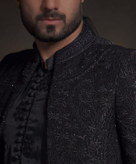 Extreme close-up of Arsalan Iqbal midnight black luxury sherwani showing intricate tonal black embroidery, sequin work, and fabric-covered buttons on a silk kurta.