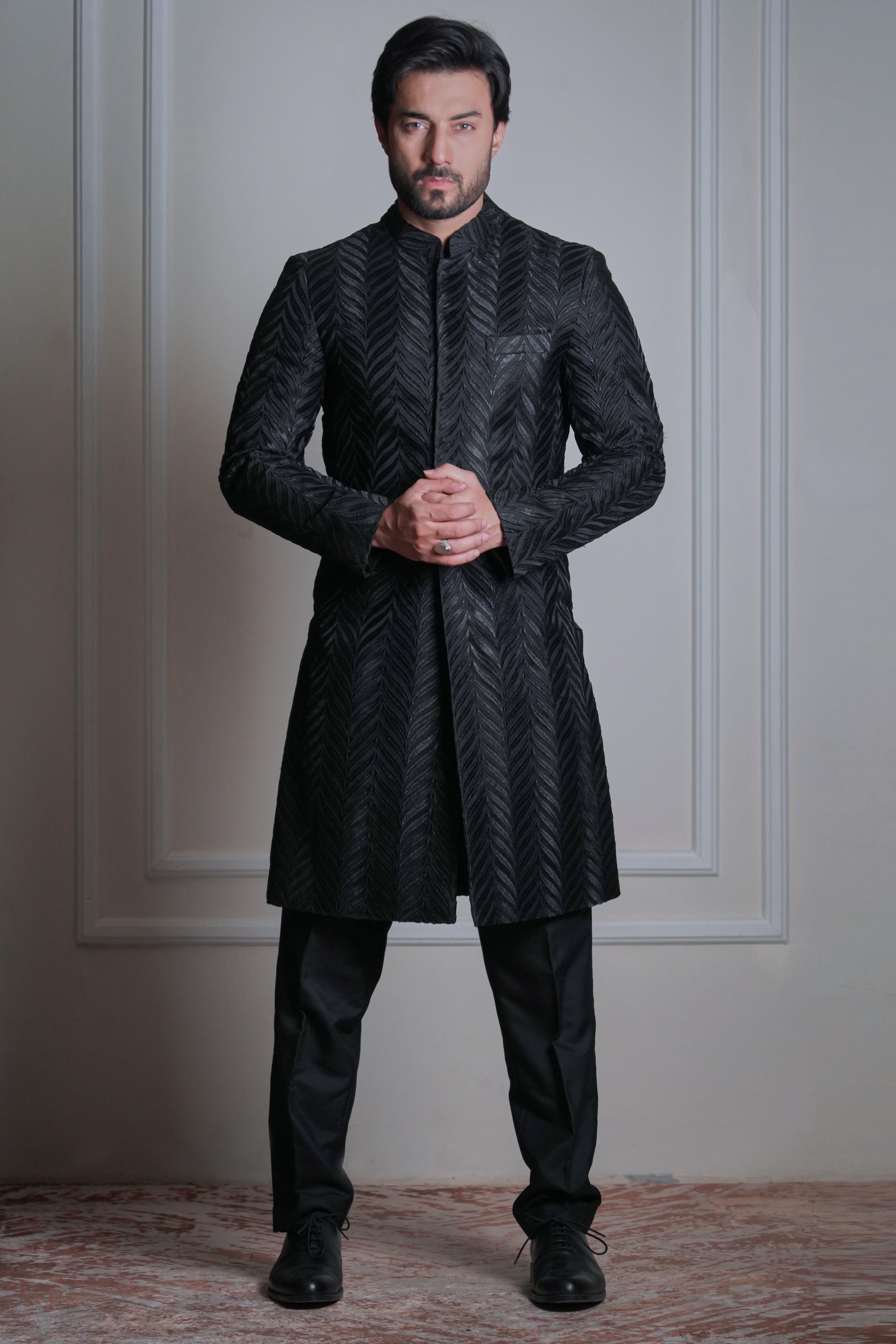 Male model wearing a black textured sherwani by Arsalan Iqbal, premium formal ethnic menswear with modern tailoring.