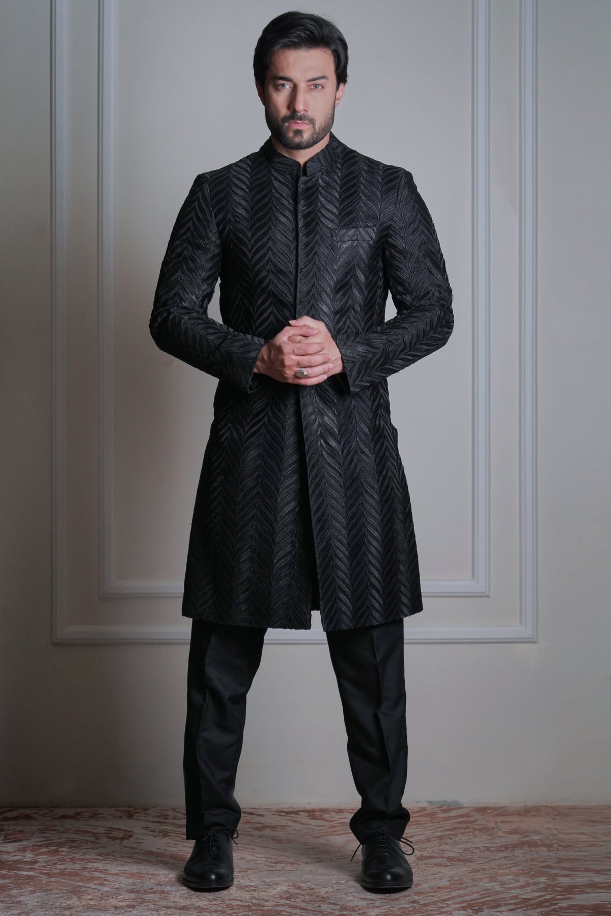Male model wearing a black textured sherwani by Arsalan Iqbal, premium formal ethnic menswear with modern tailoring.