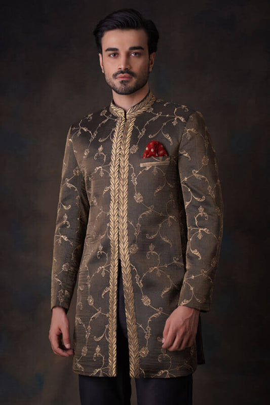 Arsalan Iqbal bronze-olive sherwani with gold ivy tilla embroidery, featuring a leaf-patterned mandarin collar and a crimson red pocket square.