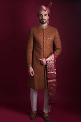 Arsalan Iqbal luxury copper-brown sherwani with black geometric micro-motifs, featuring a gold-embroidered mandarin collar and cuffs, paired with a maroon Banarasi shawl and turban.