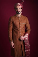Arsalan Iqbal copper-brown sherwani with black geometric motifs, featuring a gold-studded mandarin collar, maroon Banarasi shawl, and a matching silk turban.
