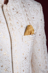 Macro detail of Arsalan Iqbal ivory sherwani featuring vertical gold sequin star patterns, white thread-work embroidery, and a mustard yellow silk pocket square.