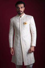 Stately frontal mid-shot of Arsalan Iqbal luxury ivory sherwani featuring intricate vertical gold star embroidery, a yellow silk pocket square, and structured shoulder tailoring.