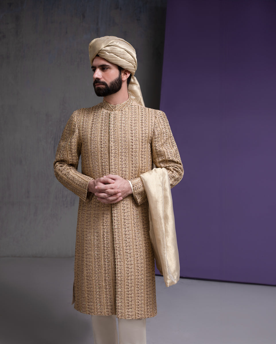 Arsalan Iqbal designer gold embroidered sherwani for men, featuring intricate vertical patterns, paired with a matching beige turban and silk dupatta.
