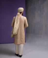 Back view of Arsalan Iqbal gold embroidered sherwani for men, showing the detailed vertical thread work and the elegant drape of a beige silk turban.