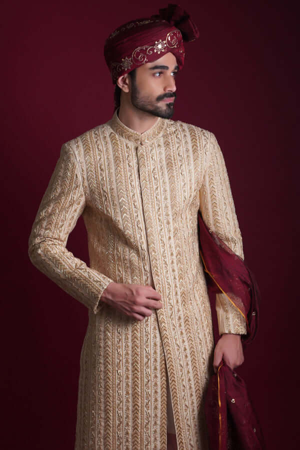 Arsalan Iqbal cream and gold sherwani with architectural chevron tilla embroidery, featuring a model in a maroon embroidered turban holding a matching shawl.