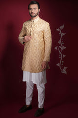 Arsalan Iqbal champagne gold prince coat with large floral damask embroidery, worn over a long white kurta and trousers.
