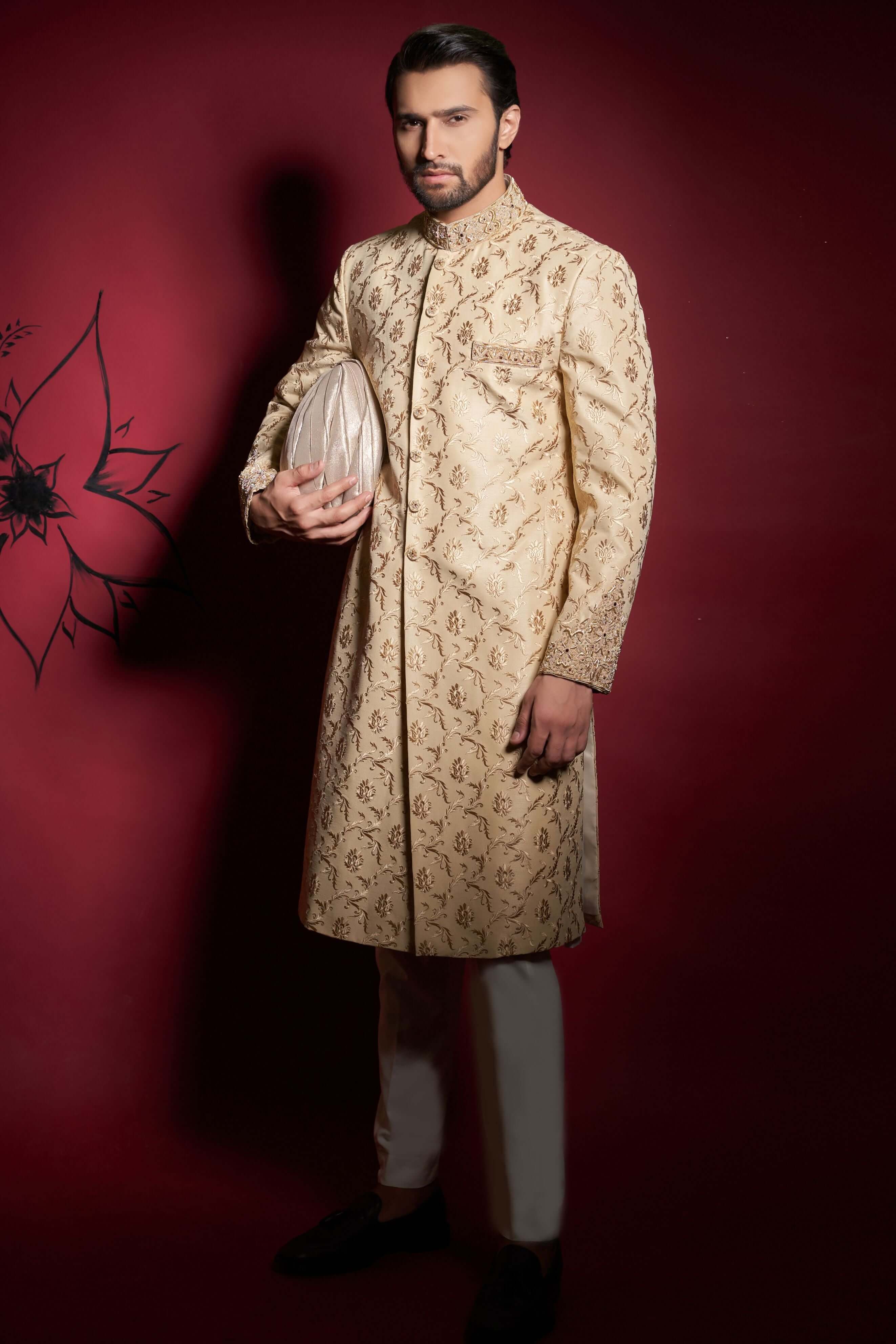 Arsalan Iqbal champagne gold silk sherwani with floral ivy tilla embroidery, featuring a model holding a matching silk turban and wearing ivory trousers.