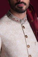 Extreme close-up of Arsalan Iqbal ivory damask sherwani collar featuring intricate paisley embroidery in maroon, gold, and blue, with embossed metallic buttons and a self-patterned silk fabric.