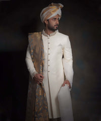 Arsalan Iqbal luxury ivory sherwani with a diamond-textured weave, featuring an embroidered collar, paired with a gold and grey patterned silk shawl and a matching gold-striped ivory turban.