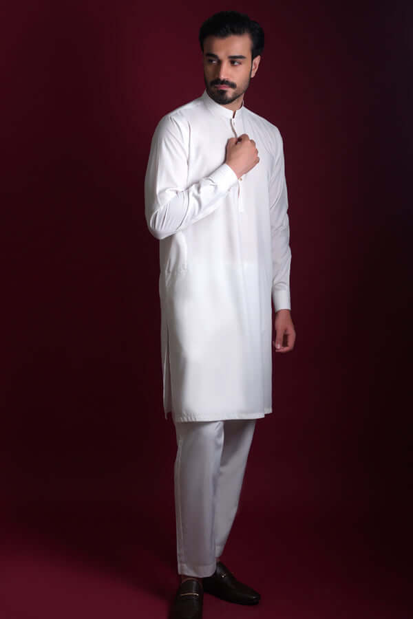 Full-length side view of Arsalan Iqbal luxury ivory silk kurta-pyjama featuring a mandarin collar and concealed placket, paired with straight-cut white trousers and dark formal loafers.