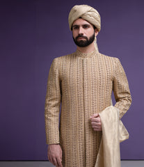 Arsalan Iqbal luxury gold sherwani for men featuring intricate hand-crafted vertical embroidery, paired with a beige silk turban and dupatta, front medium shot.