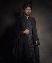 Half-length portrait of Arsalan Iqbal midnight black luxury sherwani, featuring tonal black embroidery and a matching sequined turban with a draped velvet shawl.