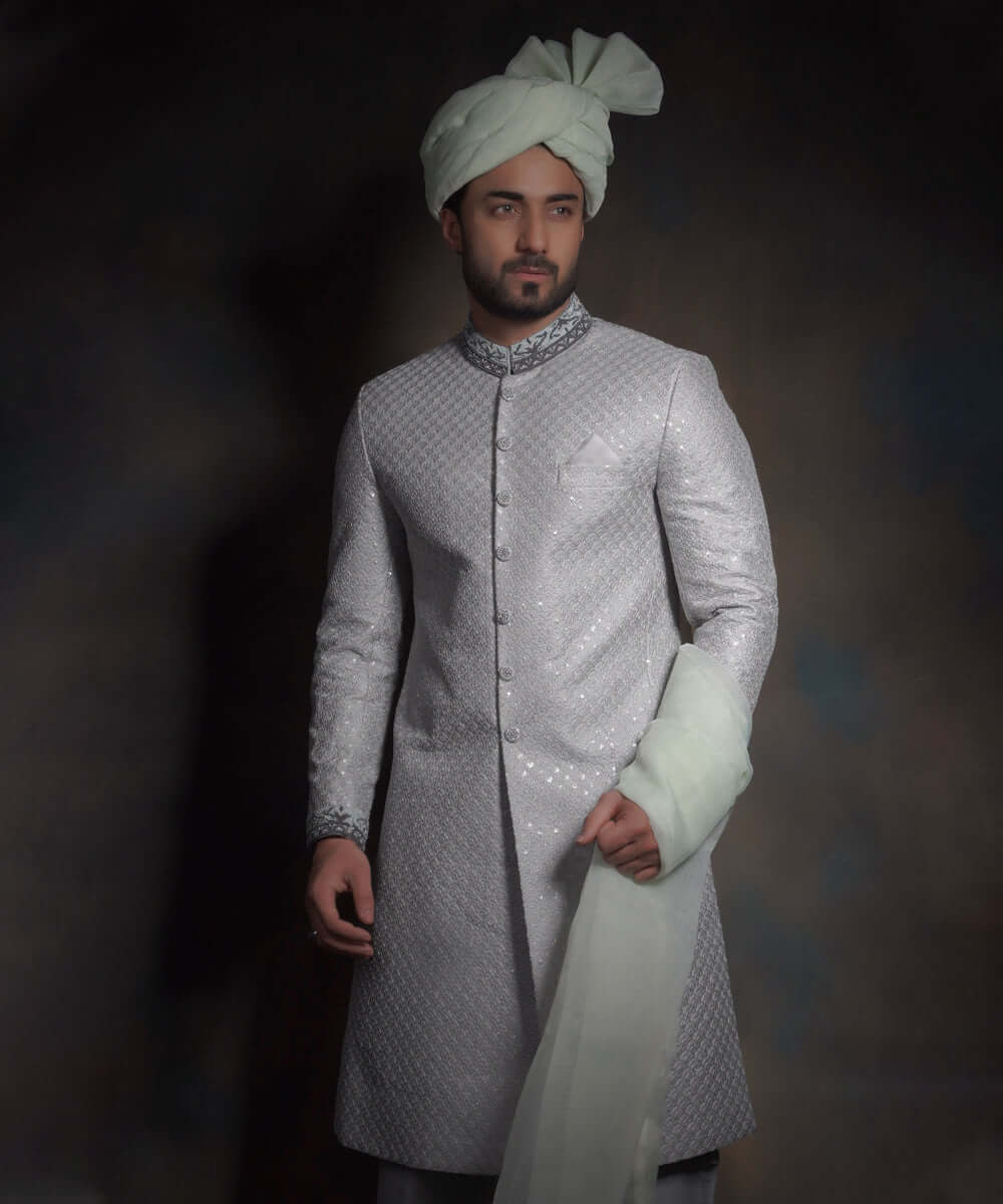 Mid-length view of Arsalan Iqbal mint green luxury sherwani with silver geometric embroidery, a charcoal grey embroidered collar, and a matching mint green turban with fan-fold styling.