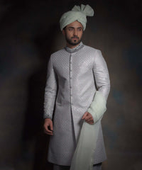 Mid-length view of Arsalan Iqbal mint green luxury sherwani with silver geometric embroidery, a charcoal grey embroidered collar, and a matching mint green turban with fan-fold styling.