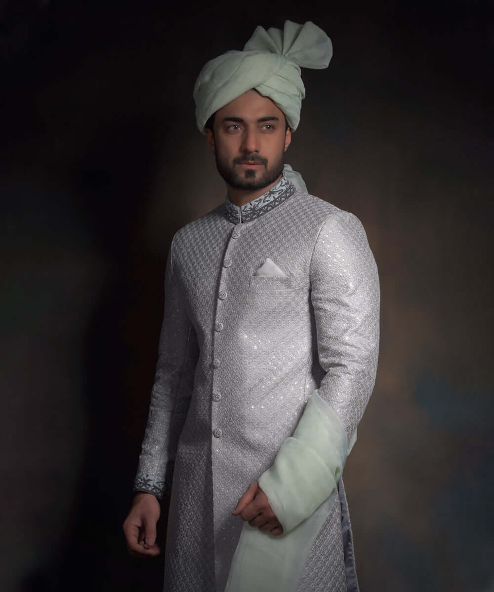 Arsalan Iqbal light mint green luxury sherwani with silver geometric patterns, featuring a charcoal grey embroidered mandarin collar, a white pocket square, and a matching mint turban.