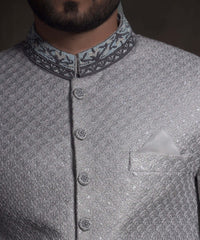 Close-up of Arsalan Iqbal mint green sherwani with silver geometric embroidery, featuring a charcoal grey mandarin collar with intricate silver threadwork and matching embroidered fabric buttons.