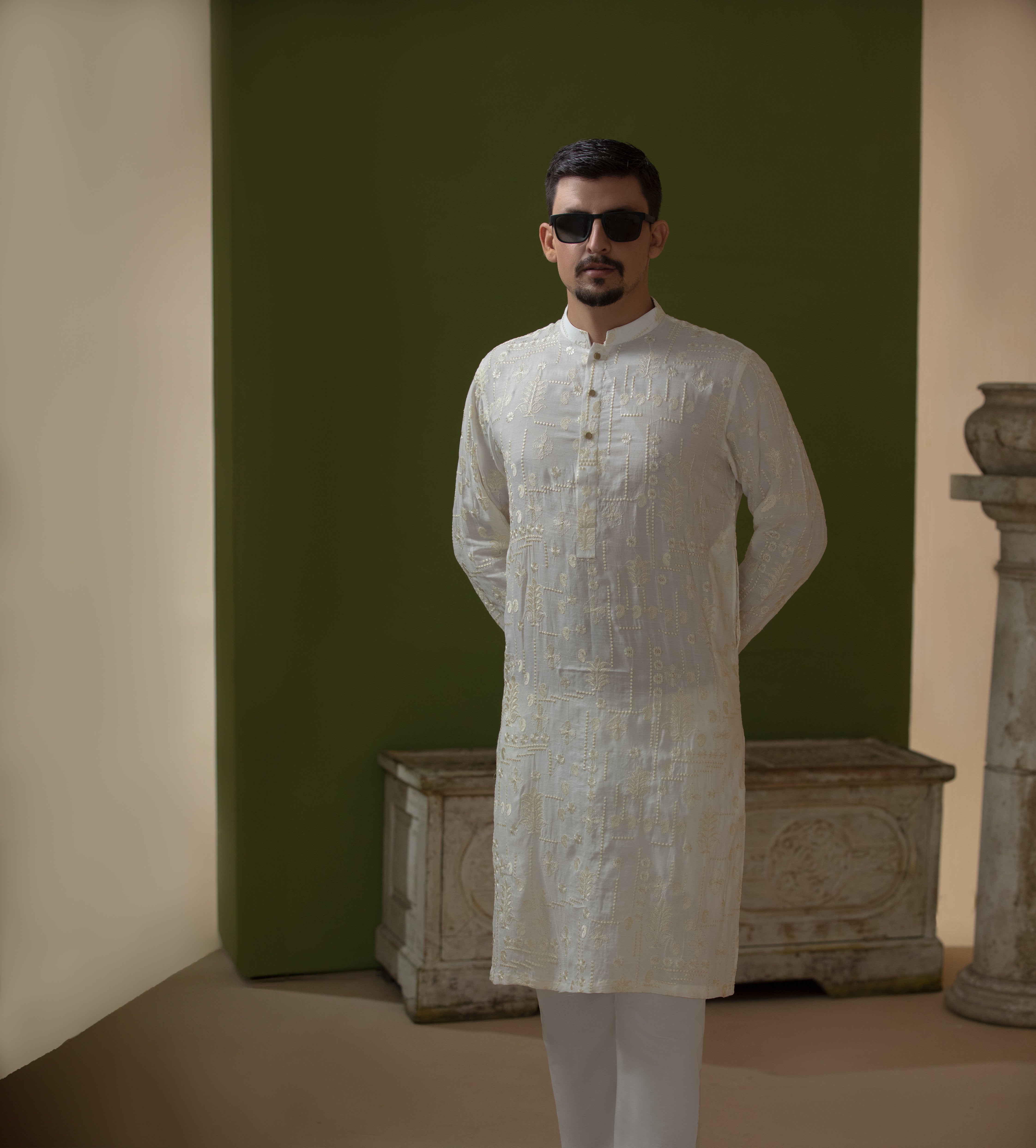 Man wearing Arsalan Iqbal's Off-White Ivory Kurta with allover silver and gold sequin embroidery, styled with black sunglasses against a deep green background
