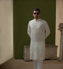 Man wearing Arsalan Iqbal's Off-White Ivory Kurta with allover silver and gold sequin embroidery, styled with black sunglasses against a deep green background