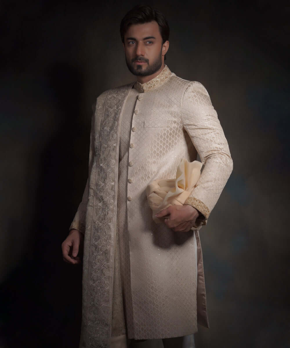Arsalan Iqbal luxury pearl cream sherwani featuring a diamond-quilted pattern, an embroidered mandarin collar, and a matching draped shawl with intricate border work.