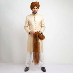 Full-length studio shot of a man in an Arsalan Iqbal black textured sherwani with a red pocket square, maroon turban, and white trousers.